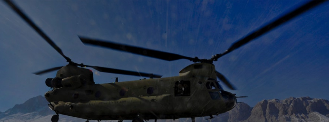 CH-47 Chinook helicopter in flight above mountainous terrain